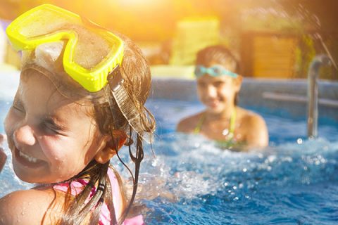 Family swimming in backyard pool